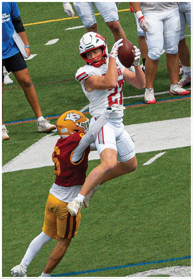 A group of people wearing red sports jerseys are sitting closely together, with one person in the center looking down thoughtfully. Description generated by AI
