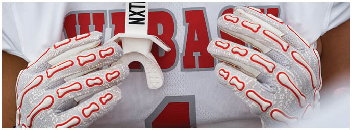 A group of people wearing white helmets with red “W" logos and red sports uniforms are huddled together on a green field. Description generated by AI