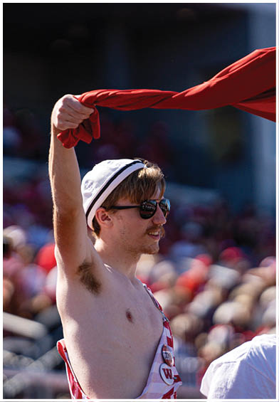 A person with a towel draped over their head is holding a green megaphone close to their mouth while wearing a headband with the word “BATTLE" on it. Description generated by AI