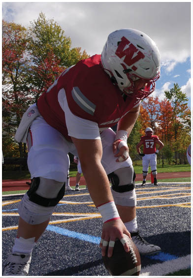 A group of people wearing red sports jerseys are sitting closely together, with one person in the center looking down thoughtfully. Description generated by AI