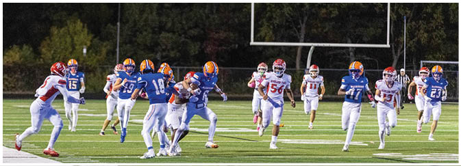 A group of football players on a field. Description generated by AI