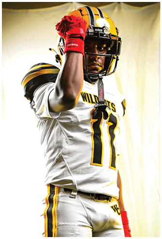 A person wearing a football uniform with the number 11 and a helmet is raising a red-gloved fist near their face. Descripci n generada con IA