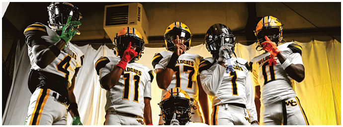 Five people wearing white and yellow Wildcats football uniforms pose confidently against a yellow and white draped background. Descripci n generada con IA