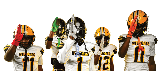 Five people wearing Wildcats football uniforms and helmets stand in a row with one hand raised in front of a yellow backdrop. Descripci n generada con IA