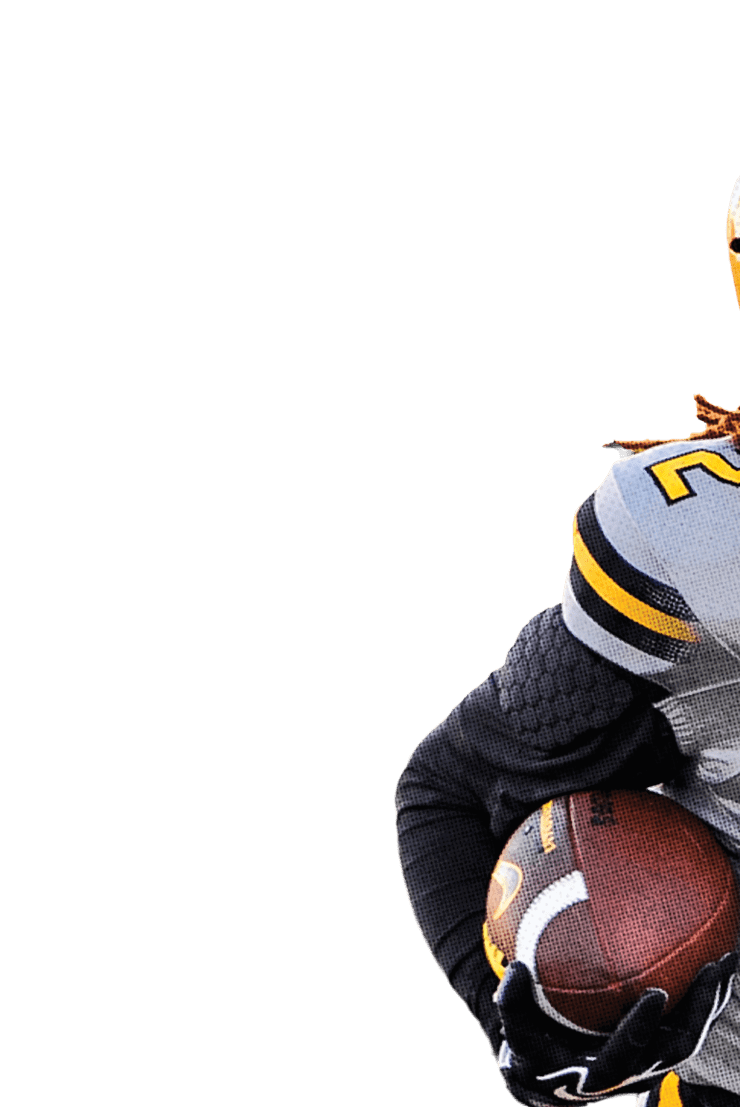 A person wearing a gray and yellow Wildcats football uniform with the number 2 is holding a football and appears to be running on a field. Descripci n generada con IA