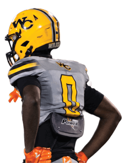 A person wearing a gray and yellow football uniform with the number 0 stands on a field with hands on hips, wearing bright orange gloves and cleats. Descripci n generada con IA