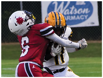 Two people in red football uniforms are tackling a person in a white and yellow football uniform on a grassy field while another person in a red uniform watches nearby. Descripci n generada con IA