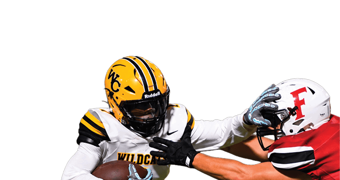 A person in a yellow and white football uniform with a helmet is running with the ball while using a stiff arm to block a person in a red and white football uniform on a grassy field. Descripci n generada con IA