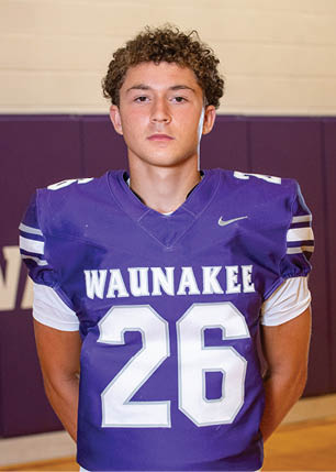 A young man wearing a white and black jersey with the number 14 on it. Description generated by AI