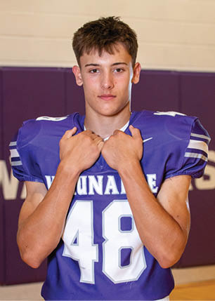A young man wearing a white and black jersey with the number 14 on it. Description generated by AI