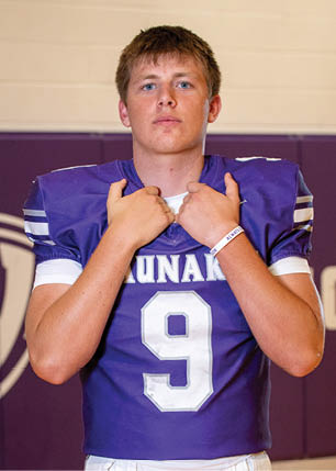 A young man wearing a white and black jersey with the number 14 on it. Description generated by AI