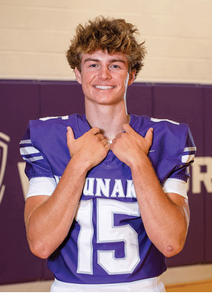 A young man wearing a white and black jersey with the number 14 on it. Description generated by AI