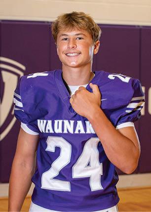 A young man wearing a white and black jersey with the number 14 on it. Description generated by AI