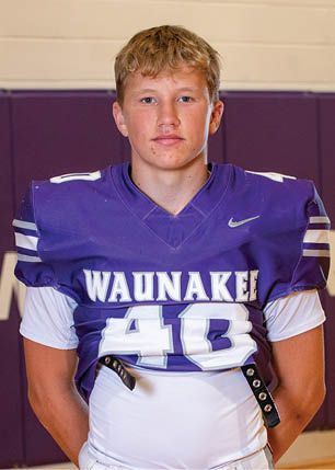 A young man wearing a white and black jersey with the number 14 on it. Description generated by AI