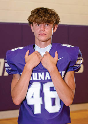A young man wearing a white and black jersey with the number 14 on it. Description generated by AI