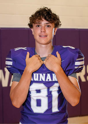 A young man wearing a white and black jersey with the number 14 on it. Description generated by AI