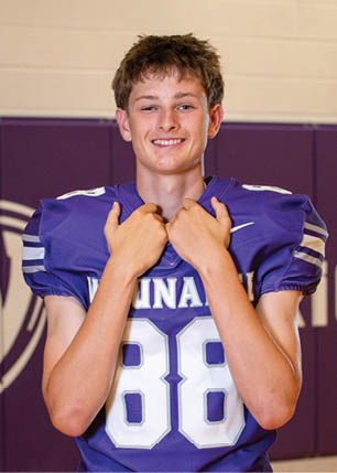 A young man wearing a white and black jersey with the number 14 on it. Description generated by AI