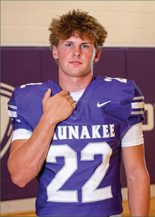 A young man wearing a white and black jersey with the number 14 on it. Description generated by AI