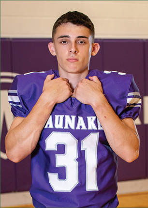 A young man wearing a white and black jersey with the number 14 on it. Description generated by AI