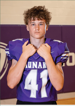 A young man wearing a white and black jersey with the number 14 on it. Description generated by AI