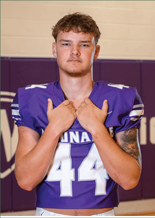 A young man wearing a white and black jersey with the number 14 on it. Description generated by AI