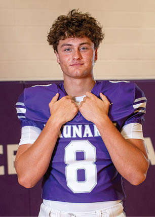 A young man wearing a white and black jersey with the number 14 on it. Description generated by AI