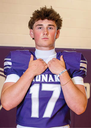 A young man wearing a white and black jersey with the number 14 on it. Description generated by AI