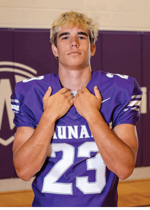 A young man wearing a white and black jersey with the number 14 on it. Description generated by AI