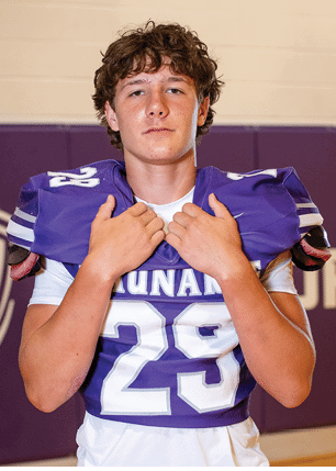 A young man wearing a white and black jersey with the number 14 on it. Description generated by AI