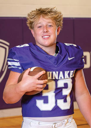 A young man wearing a white and black jersey with the number 14 on it. Description generated by AI