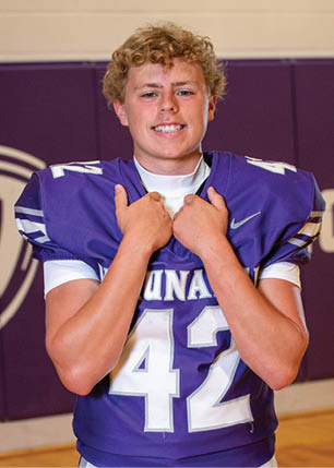 A young man wearing a white and black jersey with the number 14 on it. Description generated by AI