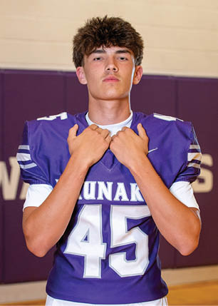 A young man wearing a white and black jersey with the number 14 on it. Description generated by AI