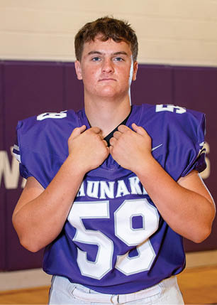 A young man wearing a white and black jersey with the number 14 on it. Description generated by AI