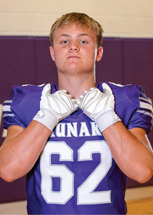 A young man wearing a white and black jersey with the number 14 on it. Description generated by AI