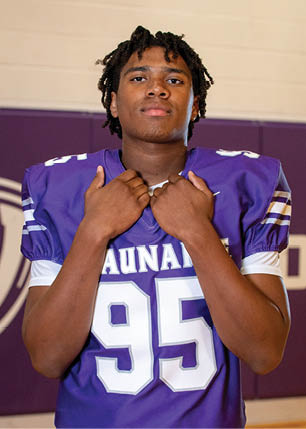 A young man wearing a white and black jersey with the number 14 on it. Description generated by AI