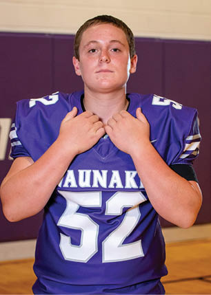 A young man wearing a white and black jersey with the number 14 on it. Description generated by AI
