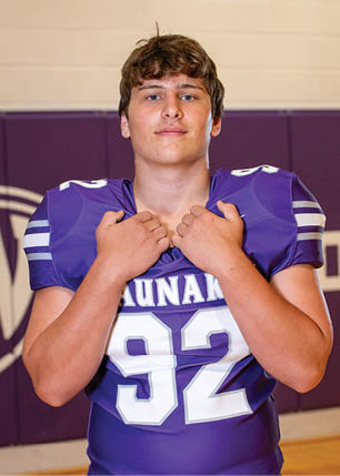 A young man wearing a white and black jersey with the number 14 on it. Description generated by AI