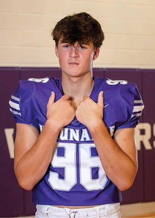 A young man wearing a white and black jersey with the number 14 on it. Description generated by AI