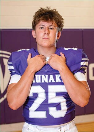 A young man wearing a white and black jersey with the number 14 on it. Description generated by AI