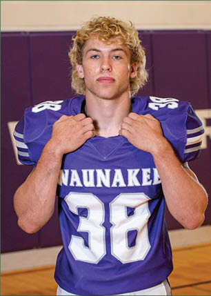 A young man wearing a white and black jersey with the number 14 on it. Description generated by AI
