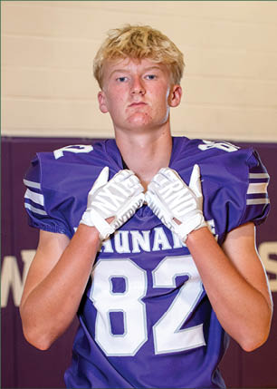 A young man wearing a white and black jersey with the number 14 on it. Description generated by AI