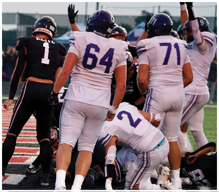 A group of football players huddled together on the field. Description generated by AI