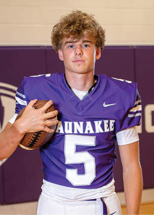 A young man wearing a white and black jersey with the number 14 on it. Description generated by AI