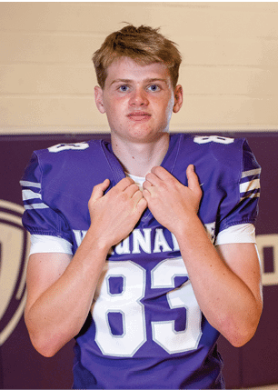 A young man wearing a white and black jersey with the number 14 on it. Description generated by AI