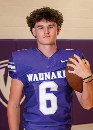 A young man wearing a white and black jersey with the number 14 on it. Description generated by AI