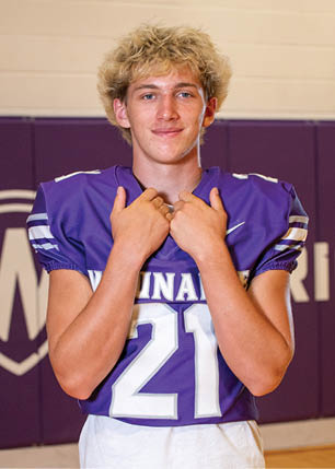 A young man wearing a white and black jersey with the number 14 on it. Description generated by AI