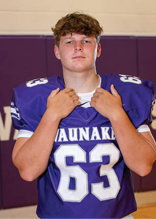A young man wearing a white and black jersey with the number 14 on it. Description generated by AI