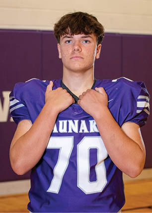 A young man wearing a white and black jersey with the number 14 on it. Description generated by AI
