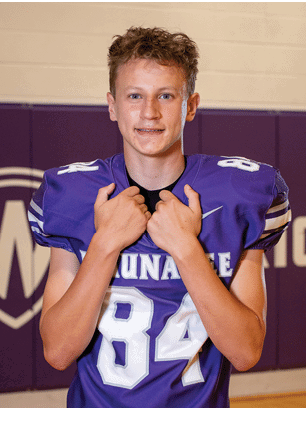 A young man wearing a white and black jersey with the number 14 on it. Description generated by AI