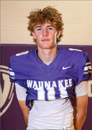 A young man wearing a white and black jersey with the number 14 on it. Description generated by AI